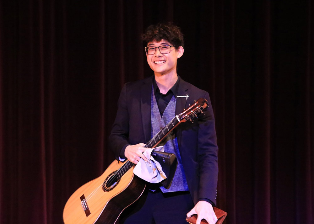 A student competitor holding a classical guitar