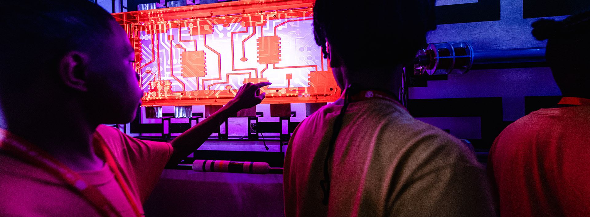 people in front of a glowing circuit board
