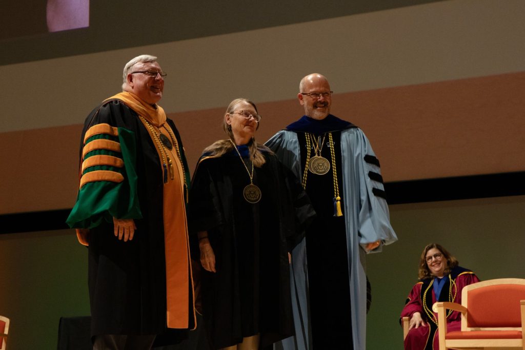 Dr. Erika Doss, the Edith O'Donnell Distinguished Chair, is pictured next to Dr. Richard C. Benson, President of the University of Texas at Dallas, on her left, and Dr. Nils Roemer, Dean of the Bass School faculty, on her right.