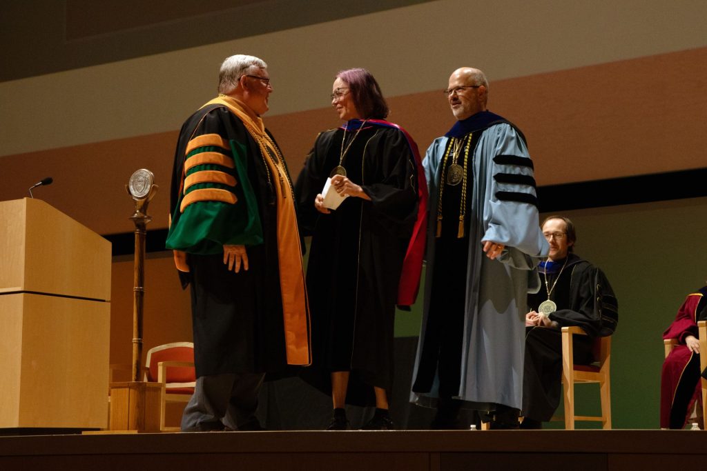 Dr. Charissa N. Terranova, Margaret M. McDermott Distinguished Chair of Art and Aesthetic Studies, is pictured next to Dr. Richard C. Benson, President of the University of Texas at Dallas, on her left, and Dr. Nils Roemer, Dean of the Bass School faculty, on her right.