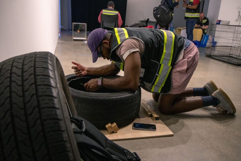 A grad student working on his project in a safety vest making changes to a tire.